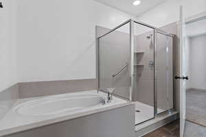 Full bathroom with a shower stall, a bath, and dark wood-type flooring
