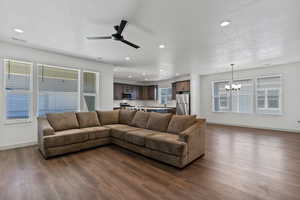 Living room with a ceiling fan, dark wood-style floors, recessed lighting, and a chandelier