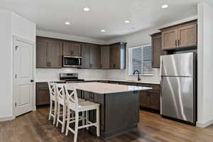Kitchen with stainless steel appliances, a kitchen breakfast bar, a kitchen island, recessed lighting, and backsplash