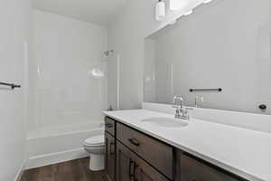 Full bathroom with vanity, bathing tub / shower combination, and dark wood-style floors
