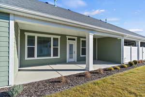 Back of property featuring a shingled roof and a patio