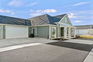 View of front of home with a shingled roof, concrete driveway, an attached garage, and covered porch