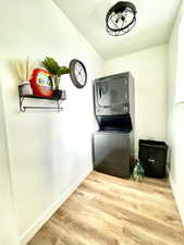 Washroom featuring stacked washer / drying machine and light wood-type flooring
