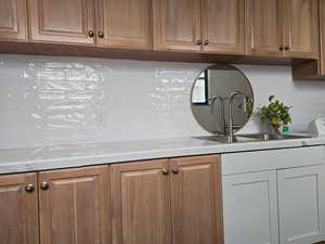 Kitchen featuring backsplash, washer / dryer, and brown cabinets