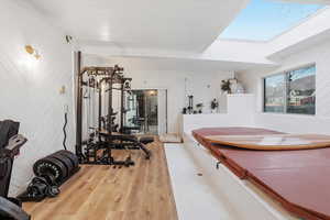 Workout area with wood finished floors, a skylight, and wood walls