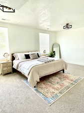 Carpeted bedroom with multiple windows and a textured ceiling