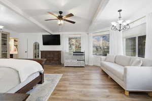 Bedroom featuring beamed ceiling, light wood-style floors, a chandelier, a ceiling fan, and a crib