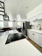 Kitchen with tile countertops, decorative backsplash, a textured ceiling, stainless steel appliances, and white cabinetry