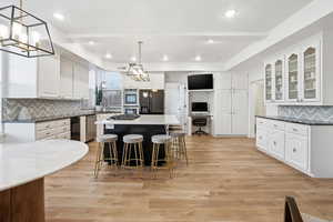 Kitchen with decorative backsplash, a chandelier, stainless steel appliances, light wood-type flooring, and recessed lighting