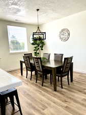 Dining area with a textured ceiling and light wood-type flooring