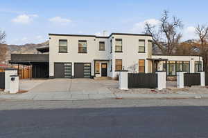 Modern home with a fenced front yard, concrete driveway, stucco siding, an attached garage, and a carport