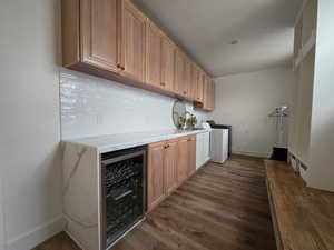 Laundry area featuring wine cooler, cabinet space, dark wood-type flooring, and washing machine and dryer