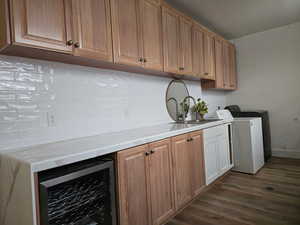 Kitchen featuring wine cooler, dark wood-style flooring, decorative backsplash, and brown cabinetry