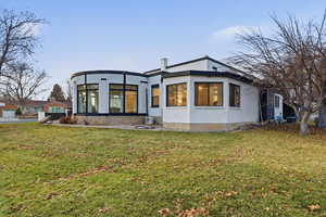 Back of property featuring a lawn, a sunroom, and stucco siding