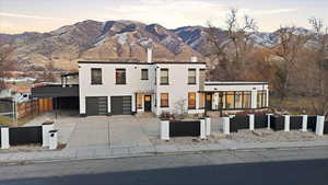 Modern home with a fenced front yard, concrete driveway, stucco siding, a mountain view, and a garage