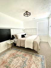 Carpeted bedroom with a decorative wall and a textured ceiling