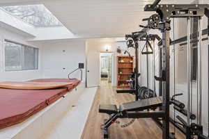 Workout room with wood finished floors, a skylight, and wooden walls