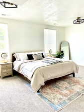 Carpeted bedroom featuring a textured ceiling and multiple windows