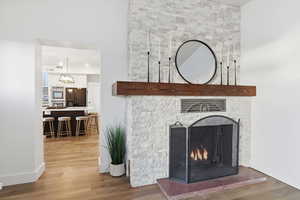 Detailed view of wood finished floors, black fridge with ice dispenser, a large fireplace, and stainless steel double oven