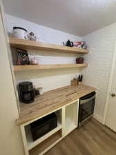 Bar with butcher block countertops, open shelves, a textured ceiling, dark wood-style floors, and black microwave