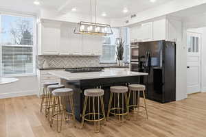 Kitchen featuring a kitchen breakfast bar, decorative light fixtures, white cabinets, a kitchen island, and stainless steel appliances