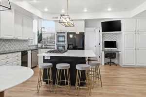 Kitchen featuring an office area, a kitchen island, stainless steel appliances, decorative backsplash, and recessed lighting