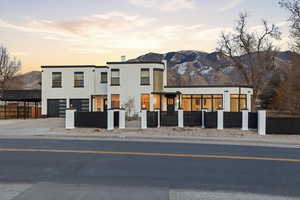 Contemporary home featuring a fenced front yard, a mountain view, driveway, stucco siding, and a garage