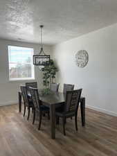 Dining space with a textured ceiling, wood finished floors, and a chandelier