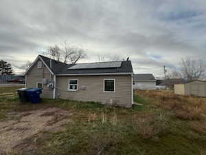 Back of house featuring roof mounted solar panels and a storage shed