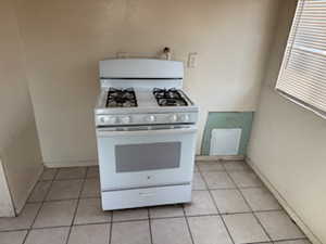 Kitchen with white range with gas cooktop and light tile patterned floors