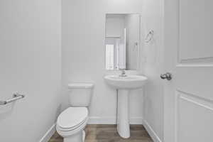 Half bath with toilet and wood finished floors