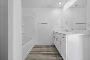 Bathroom with vanity, dark wood-style flooring, and shower / tub combination