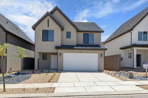 View of front of house featuring concrete driveway, stucco siding, a tile roof, and an attached garage
