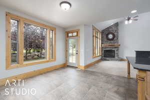 Unfurnished living room with a fireplace, lofted ceiling, and ceiling fan