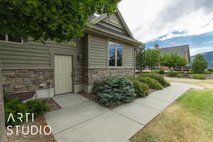View of exterior entry featuring stone siding and a yard