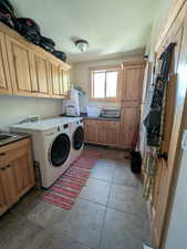 Laundry room with cabinet space, a textured ceiling, washer and dryer, and light tile patterned floors