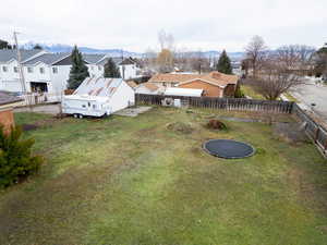 Fenced backyard featuring a trampoline and a residential view