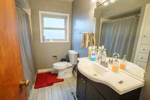 Full bath featuring vanity, curtained shower, and wood finish floors