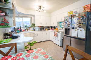 Kitchen with stainless steel appliances, light countertops, white cabinetry, a textured ceiling, and open shelves
