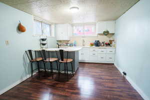 Kitchen with a peninsula, light countertops, a breakfast bar, and dark wood finished floors