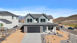 View of front facade featuring a mountain view, a garage, concrete driveway, board and batten siding, and stone siding