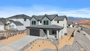 Modern farmhouse featuring concrete driveway, stucco siding, an attached garage, a porch, and stone siding