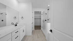 Full bath with a shower stall, double vanity, a spacious closet, and recessed lighting