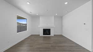 Unfurnished living room with dark wood-type flooring, a large fireplace, and recessed lighting