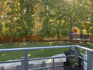 Fenced backyard featuring a trampoline