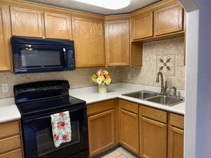 Kitchen featuring black appliances, light countertops, brown cabinetry, and backsplash