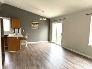 Kitchen featuring brown cabinets, a chandelier, vaulted ceiling, light countertops, and dark wood-type flooring