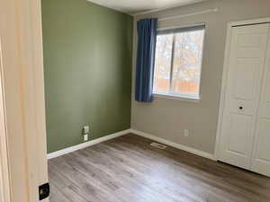 Unfurnished bedroom with wood finished floors and a closet