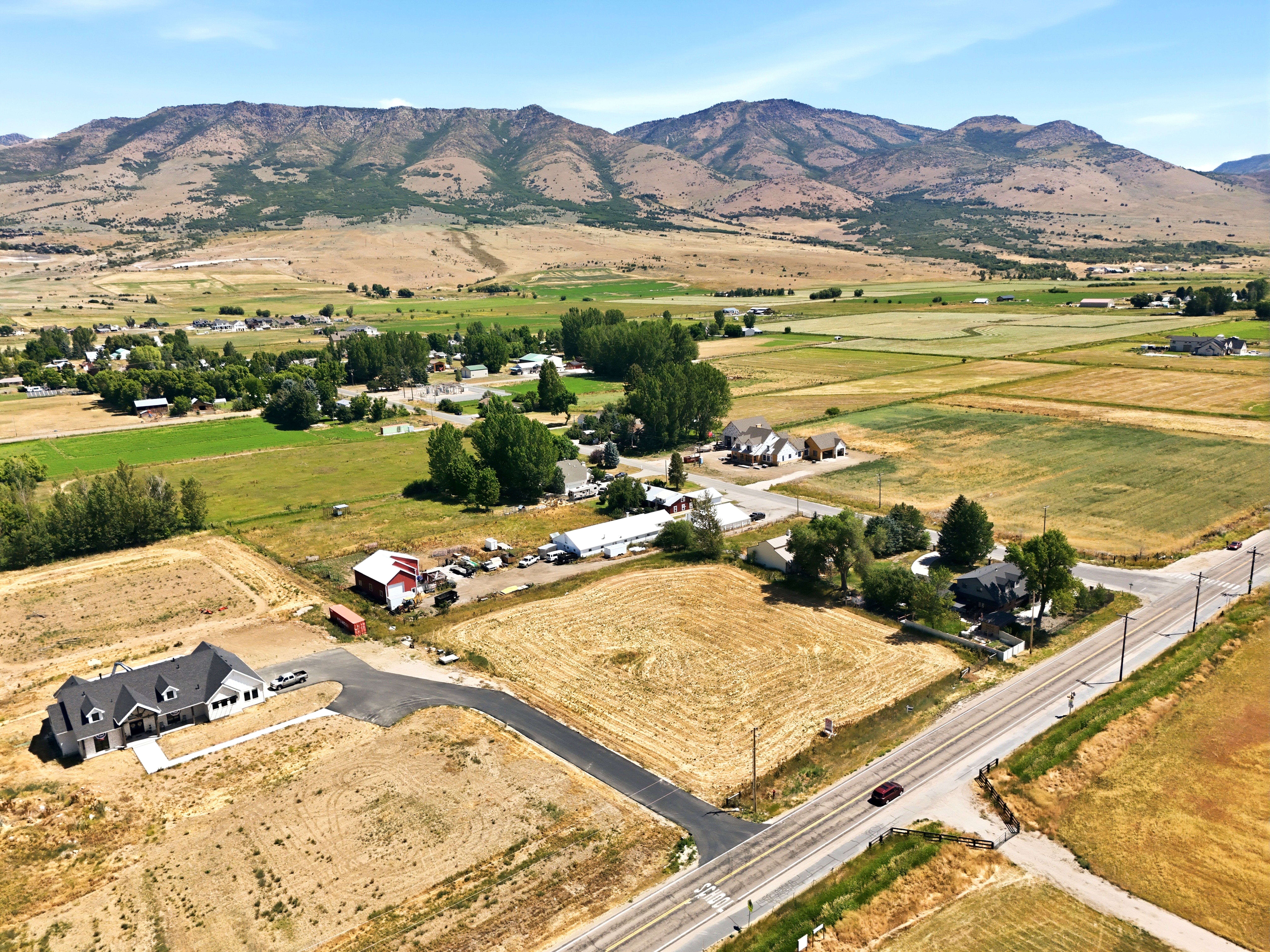 Aerial perspective showcasing a new construction residence with a black shingle roof and light-colored siding