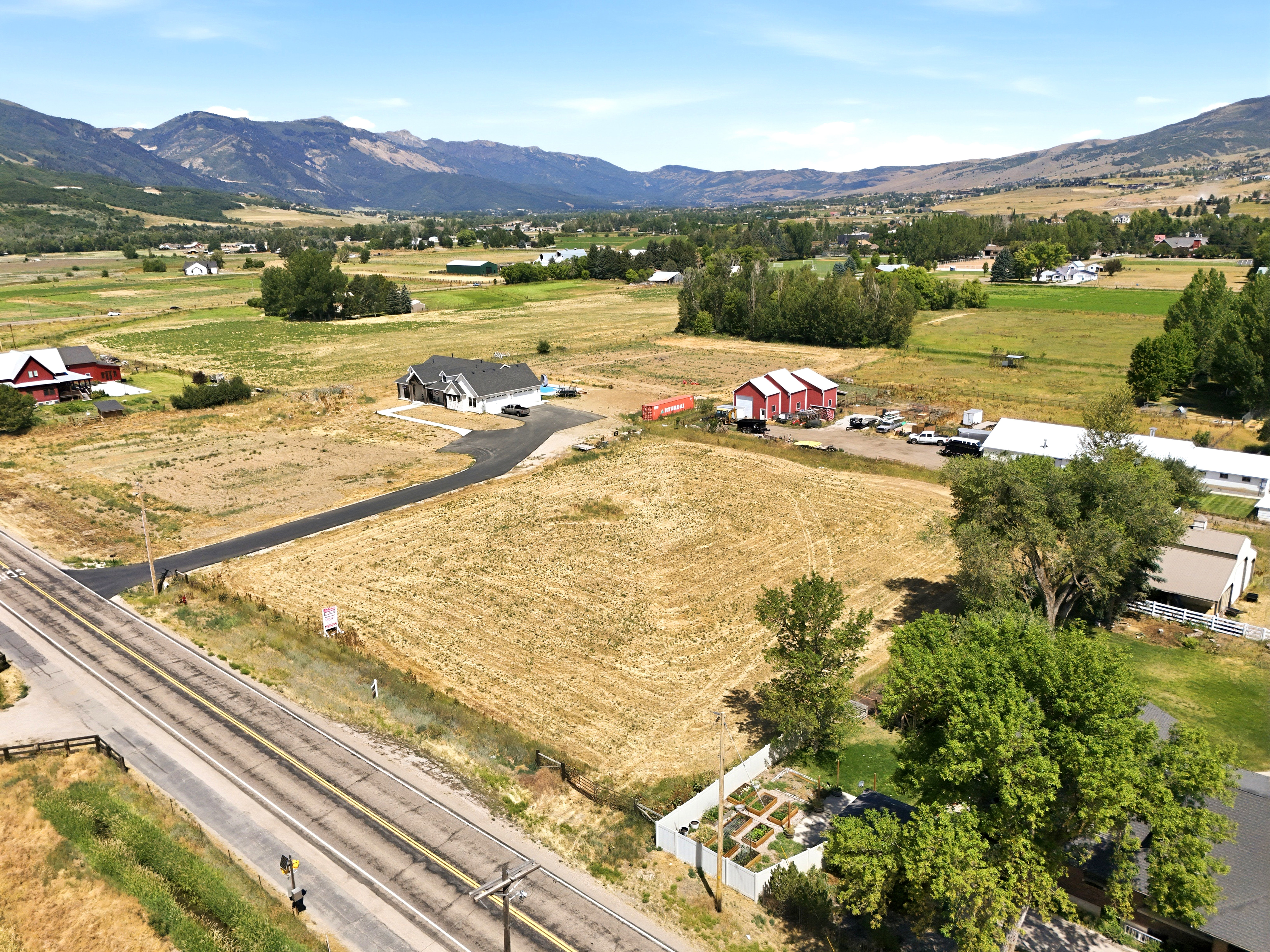 Expansive property featuring a contemporary residence with a dark roof, paved driveway, and surrounding agricultural land